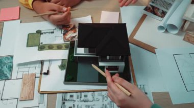 İki mimar detaylı bir ev tasarımı projesinde işbirliği yaparak, bir çalışma alanı üzerinde modeller ve çizimler yaparak, mimaride yaratıcılık ve takım çalışması sergilediler. SACTR