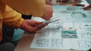 Bir grup tasarımcı detaylı mimari planlar ve bir stüdyoda minyatür bir model üzerinde işbirliği yapıyorlar. Tasarım süreçlerinde takım çalışması ve yaratıcılığa vurgu yapılıyor. SACTR