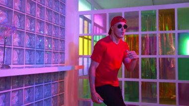 Komik break dansçı kameraya bakarken hiphop 'a doğru serbest adım atıyor. Çılgın mutlu hipster dans edip sokak dansı yaparken Led ışığında günlük kıyafet ve güneş gözlüğü takıyor. Mutluluk.