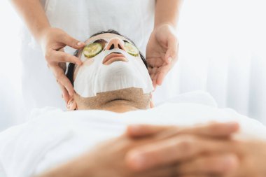 Kaplıca salonunun sakin atmosferi, insan müşterisi lüks salatalıklı yüz maskesi ile kendini yenileme zevkine kapılıyor. Yüz bakımı tedavisi ve güzellik konsepti. Sessiz.