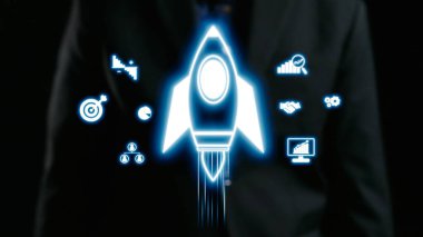 Bu resim, bir şirket ortamında başarı ve yeniliği temsil eden dijital simgelerle çevrili, büyümeyi sembolize eden bir roket içeren modern bir iş konseptini tasvir etmektedir. Dörtgen