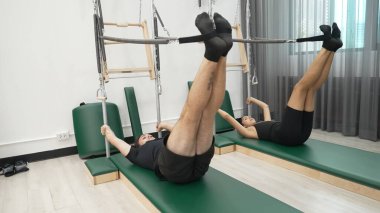 Bir grup müşteri, çekirdek dayanıklılığını ve bacak bağını geliştirmek için Cadillac reformatör makinesinde pilates egzersizleri yapıyor. Sağlıklı müşterilerin daha düşük poz verip kaldırma pozlarının üst görüntüsü. Sağlıklılık. Alışkanlık.