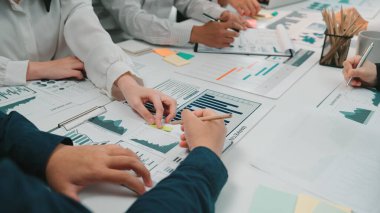 Çeşitli profesyonellerden oluşan bir grup, bir iş toplantısı sırasında çizelge ve grafikleri işbirliği içinde analiz ediyor. Sahne, takım çalışmasının ve stratejik planlamanın özünü yakalıyor. SACTR