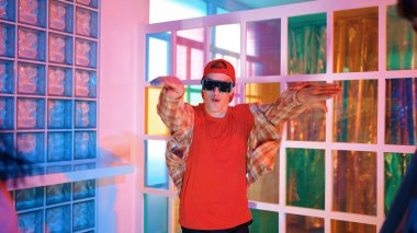 Kafkas dansçısı dans ederken çeşitli arkadaşları gece kulübünde neon ışıkta ayak seslerine bakıyor. Çoklu etnik kökenli hipsterin serbest stil müziğe geçişi ve mutlu bir adamın kameraya bakışıyla. Mutluluk.