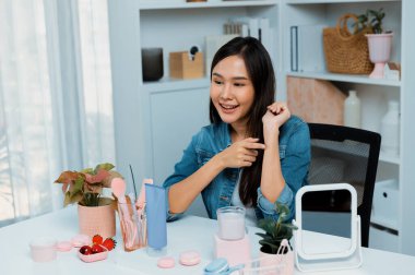 Genç, güzel Asyalı kozmetik makyaj ruju matte pastel rengini modern odadaki sosyal medyada kol testi tanıtımında en çok satanlar listesinde gösteriyor. Taktik.