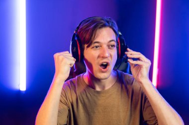 Kazanmak için çevrimiçi oyun oynayan akıllı flama makinesinin sunucu kanalı, neon ışıklı odada seçilen takım yarışması için izleyicilerle birlikte canlı yayında canlı yayında kulaklık takıyor. Bireysel.