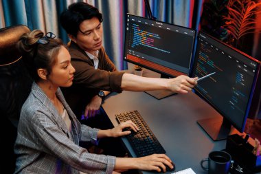 Bilgi teknolojisi geliştiricileri modern ofisteki neon ışık odasında verileri çevrimiçi olarak çalıştıran akıllı web sitesi geliştirme kodlayıcı sistemine işaret ediyorlar. İnfobahn.