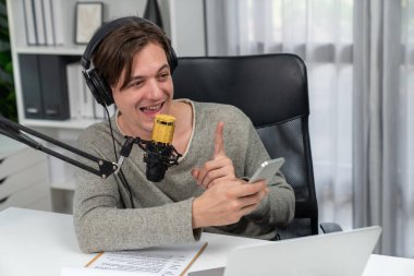 Akıllı yayıncının sunucu kanalı canlı sosyal medya yayını ile akıllı telefon kullanarak dinleyiciyle sohbet ediyor, kulaklık takarak modern ev stüdyosunda video kaydediyor. Bireysel.