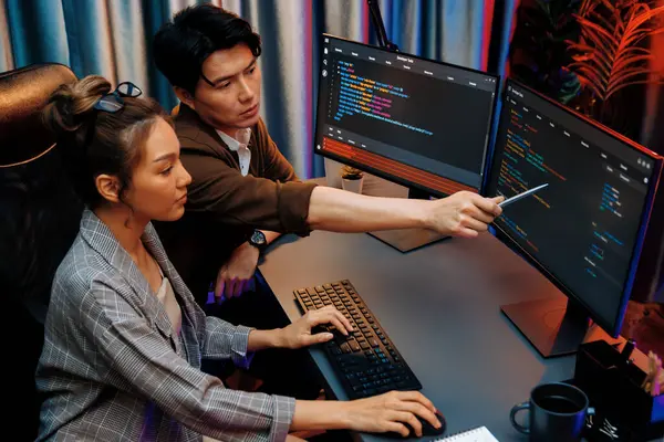 Bilgi teknolojisi geliştiricileri modern ofisteki neon ışık odasında verileri çevrimiçi olarak çalıştıran akıllı web sitesi geliştirme kodlayıcı sistemine işaret ediyorlar. İnfobahn.