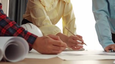 Mimari döküman, ölçüm araçları ve ahşap blokların modern ofiste etrafa saçıldığı masa üzerine planlar yapma konusunda akıllı mimar ve güvenlik mühendisi tartışması. - Yakın çekim. Tanımlama.