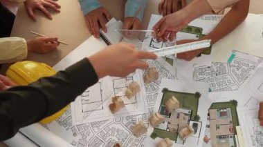 Mimari belge, ölçüm aracı ve ahşap blokların modern ofiste etrafa saçıldığı bir masa üzerinde yapı inşaatı ile ilgili mimar ve güvenlik mühendisi tartışması. Tanımlama.