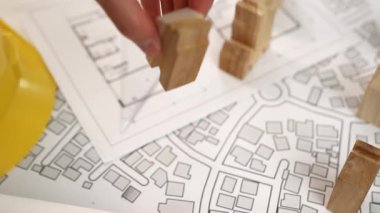 Masada sarı başlıklı mühendis videosu ev şeklindeki ahşap blok tasarım evini ölçmek için ölçü cetveli kullanıyordu. Eline odaklan. Tanımlama.