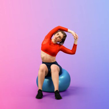 Vücut uzunluğunun tamamı atletik ve sportif genç bir bayanın izole edilmiş arka planda duran bir duruşta topa egzersiz yapmasıyla geçiyor. Sağlıklı aktif ve vücut bakımı yaşam tarzı.