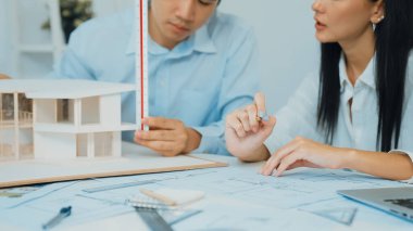 Profesyonel mühendis ev modelini tartartarken, yetenekli tasarımcı da planına yazar. Birlikte çalışmak, işbirliği, işbirliği. Yaratıcı tasarım ve takım çalışması konsepti. - Yakın çekim. Tertemiz.