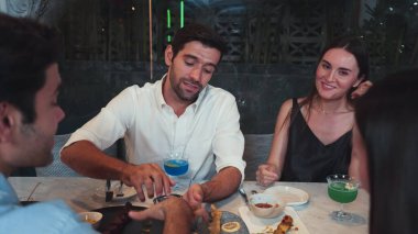 Grup arkadaşı ya da çift, ızgarada ve ana yemek masasında yemek yerken akıllı telefonla konuşuyor. Lüks restoranda etkileyici bir dostluk ortamında tanışma teması. Vinosity.