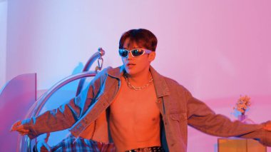 Asyalı sokak dansçısının neon ışıkla pop müziğe geçişine yakın çekim yaparken çeşitli arkadaşlar oturuyor ve performansı destekliyor. Profesyonel sanatçı stüdyoda dans figürleri yapıyor. Mutluluk.