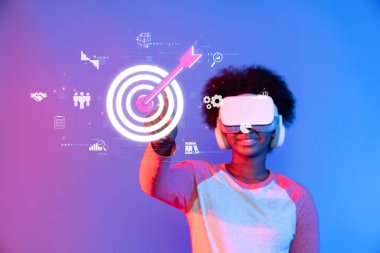 Genç bir birey, pazarlama stratejileri ve izleyicilerin ikonlar ve verilerle dolu renkli bir dijital ortama olan bağlılıklarını keşfetmek için sanal gerçeklik araçlarıyla etkileşime girer. XDMCP
