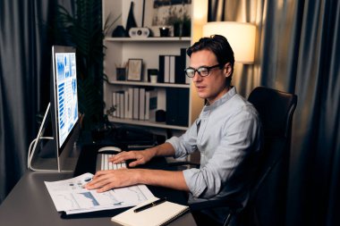 Akıllı iş adamı iş paragrafı dinamik pazarlama analizi planını analiz ediyor. Kağıt kağıtları ve bilgisayar monitörü raporlarını gece evdeki belge verileriyle karşılaştırmak için hazırlıyor. Bireysel.