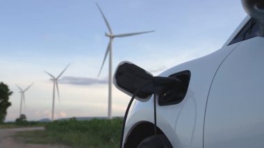 Çevreyi korumak için rüzgar türbininden yeşil ve yenilenebilir enerjiyle çalışan şarj istasyonunda şarj edilen gelişmiş gelecek enerji altyapısı konsepti.