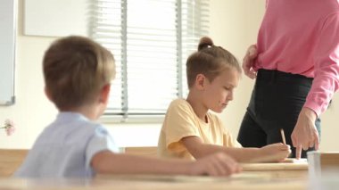 Beyaz bir çocuk ödevlerini yaparken ve açıklama dinlerken güzel bir öğretmen sınavı açıklıyor. Sınıfta not alırken ya da kağıda cevap yazarken öğretmenine bakan sevimli bir çocuk. Pedagoji.