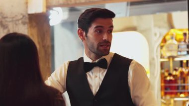 Yakışıklı, güler yüzlü bir barmen arkadaş, VIP müşterilerine içki listesi öneriyor. İçki tezgahı lüks, profesyonel barmen kostümü içinde harika bir ilk izlenim bırakıyor. Vinosity.