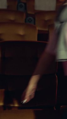 Seyirciler sinema salonundaki koltuklara yürüyor, film izliyor ve patlamış mısır yiyor..