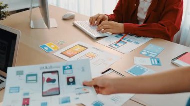 Mobil uygulama için kullanıcı arayüzü prototipini ofis çalışanlarına sunan harika bir şirket çalışanı. UX UI tasarımcısı kağıt üzerinde simge tasarımının işlevini açıklıyor. Sinerjik