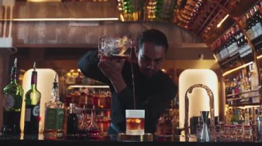 Asyalı barmen soğuk bardağa karışık viski dökerek soğutmalı buzlu içecek üretiyor. Lüks ılık barlarda alkol yenileme gösterisine odaklanan yaratıcı bir reklam yapıyor. Vinosity.