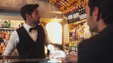 Akıllı barmen, lüks bir tezgahta arkadaşını beklerken limonlu cin kokteyli ikram ediyor. Barmen, canlı gece hayatı parti atmosferinde mükemmel hizmet veriyor. Vinosity.