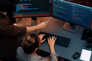 Akıllı web sitesi geliştirme kodlayıcı sistemi ile tartışan IT geliştiricilerinin üst görüşü modern ofisteki neon ışık odasında iki ekran bilgi teknolojisini çevrimiçi çalıştırıyor. İnfobahn.