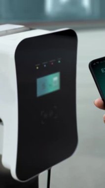 EV akıllı telefon uygulamasında EV akü durumu. Kamu şarj istasyonundan şarj olurken. EV arabaların yenilikçi teknolojik gelişimi ve alternatif enerji kullanımı. İnceleyin