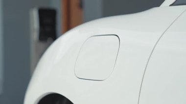 İlerici adam evindeki elektrikli aracın aküsüne emisyonsuz güç bağlantısı kuruyor. Elektrikli araç elektrik istasyonundan EV araba aküsüne kabloyla şarj oluyor.