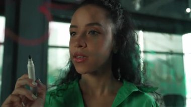 Zeki, profesyonel İspanyol iş kadınının portresi renkli yapışkan notlarla cam tahtaya pazarlama fikirleri yazıyor. Genç yönetici, analiz iş planının zihin haritasını çiziyor. - Yakın çekim. Yönlendirici.