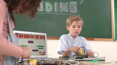 Kafkas akıllı çocuk kök teknoloji dersinde tornavida kullanarak ana tahtayı tamir ederken aynı zamanda gülümseyen öğrenci de dizüstü bilgisayar ekranı kodlu elektronik makineyi incelemek için birlikte çalışıyor. Pedagoji.