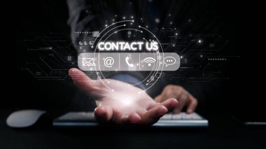 Bir el, dijital iletişim sembolleriyle çevrili, iş ve teknoloji ortamlarındaki bağlantıyı ve desteği temsil eden parıldayan bir iletişim simgesine doğru uzanıyor. Dörtgen