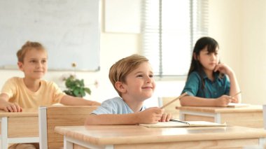 Sınıfta okuyan çeşitli çocuklarla çevrili beyaz bir çocuk öğretmenine soru sorup cevap verdiği için elini kaldırıyor. Mutlu öğrenci birlikte çalışıyor, oy veriyor, gönüllü oluyor, hocayı arıyor. Pedagoji.