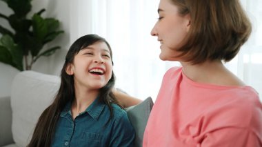 Mutlu anne oturma odasında otururken kızıyla deneyim paylaşıyor. Kafkas anne ve mutlu çocuk konuşuyorlar ve birlikte vakit geçiriyorlar. Çekici kız gülümserken ebeveyn hikayesini dinler. Pedagoji.