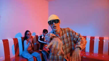 Kafkasyalı break dansçı çeşitli arkadaşlar birlikte dans ederken hareket eder. Çok kültürlü grup arkadaşını desteklemek ve cesaretlendirmek için el sallarken mutlu hipster hareketi. Mutluluk.