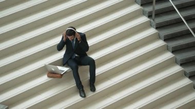 Merdivenlerde otururken kulaklıktan müzik dinleyen zeki bir iş adamı. Mutlu menajer dans ederken ya da müzikle uğraşırken gülümsüyor. Yatırımcı iyi haberler alıyor, terfi alıyor. Sevinçli..