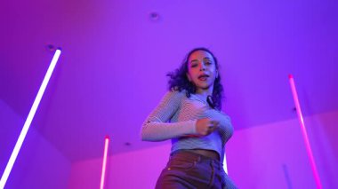 Latin dansçıların kameraya bakıp şehrin pop müziğiyle dans ettiği düşük açılı kamera. Profesyonel çekici hipster, mor veya neon ışıklı hip hop şarkısına geçiyor. Şık bir kumaş. Mutluluk.