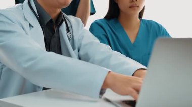 Hastane masasında birlikte çalışan ve tıbbi tedavi planlayan çeşitli profesyonel sağlık görevlileri. Takım çalışması başarılı hastalıklara ve hastalıklara yol açar. Ağır çekim. Katı.