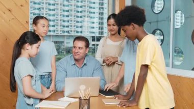 Başarılı bir proje için öğrencileri teşvik etmek ya da kutlamak için yetenekli bir öğretmen alkışlıyor. Çeşitli çocuklar profesyonel eğitmenin etrafında dururken el çırpıyorlar. Öğretim