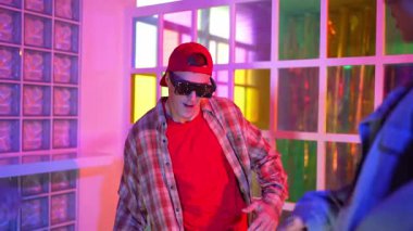 Kafkas dansçısı dans ederken çeşitli arkadaşları gece kulübünde neon ışıkta ayak seslerine bakıyor. Çoklu etnik kökenli hipsterin serbest stil müziğe geçişi ve mutlu bir adamın kameraya bakışıyla. Mutluluk.