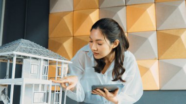 Tablet kontrol evi modelini kullanan güzel bir proje yöneticisi. Mimar mühendisinin portresi tabletteki veri analizini kullanarak bina inşaatını denetliyor. İş inşaat konsepti. Yönlendirici.