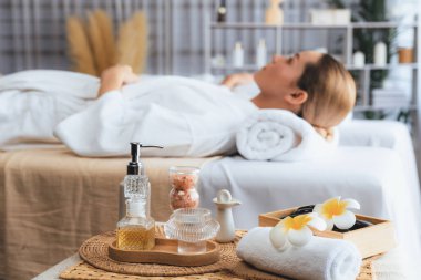 Aromaterapi masajı gündüz atmosferinde ya da spa salonunda bulanık bir kadına odak dekor ve spa aksesuarları kurarak tatil köyünde ya da otel arka planında keyifli aroma spa masajı yapan bir masaj. Sessiz.