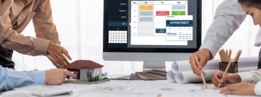 İç mimar tasarımcı grubu, daha kesin tasarım için planlar ve dizüstü bilgisayar ekran mimari yazılımı üzerinde birlikte tartışıyorlar. Modern ev tasarımı ve yenileme. İçgörü