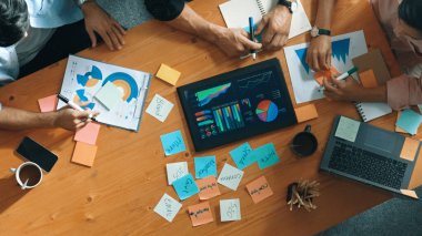 Yönetici, toplantı odasındaki meslektaşlarına mali grafiği açıklar. Farklı pazarlama ekibinin tabletle masada otururken fikir ve planlama stratejisini en üst düzeyde paylaşması. Cemaat.