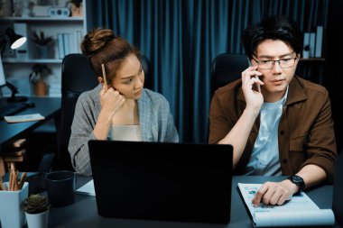 Satış müdürünün dizüstü bilgisayarında çalışan ciddi bir yüz sekreterli müşteriyi arıyor ve modern ofiste gece geç saatlerde evrak işleri ile ilgili notlar yazıyor. Aşırı çalışan problem projesi kavramı. İnfobahn.
