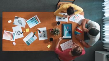 Proje yöneticisi renk paletleri seçerken tasarımcının tablete baktığı yukarıdan aşağıya hava görüntüsü. Yetenekli grafik tasarımının zaman aşımı ve logoya bak. Yetenekli ekip grafikleri seçiyor. Sempozyum.