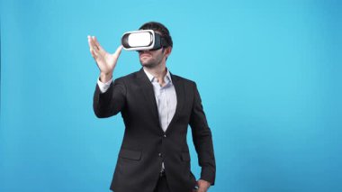 Yetenekli bir iş adamı mavi arka planda dururken hologramı tutuyor. Proje yöneticisi artırılmış gerçeklik teknolojisi kullanarak pazarlama stratejisi planlarken mali raporları kontrol ediyor. Aygıt.